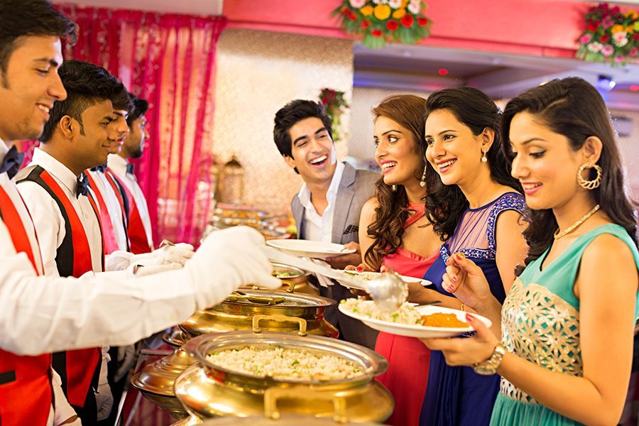 Guests served from brass chafing dishes at a wedding buffet