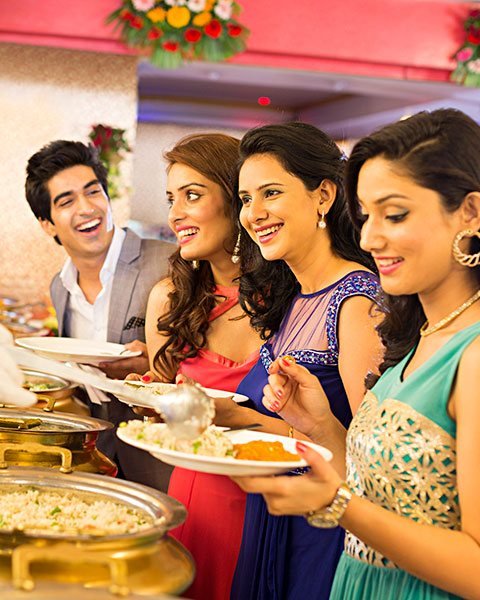 Guests being served from brass chafing dishes at a wedding buffet