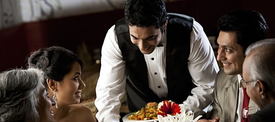 Server presenting a dish to guests at the table